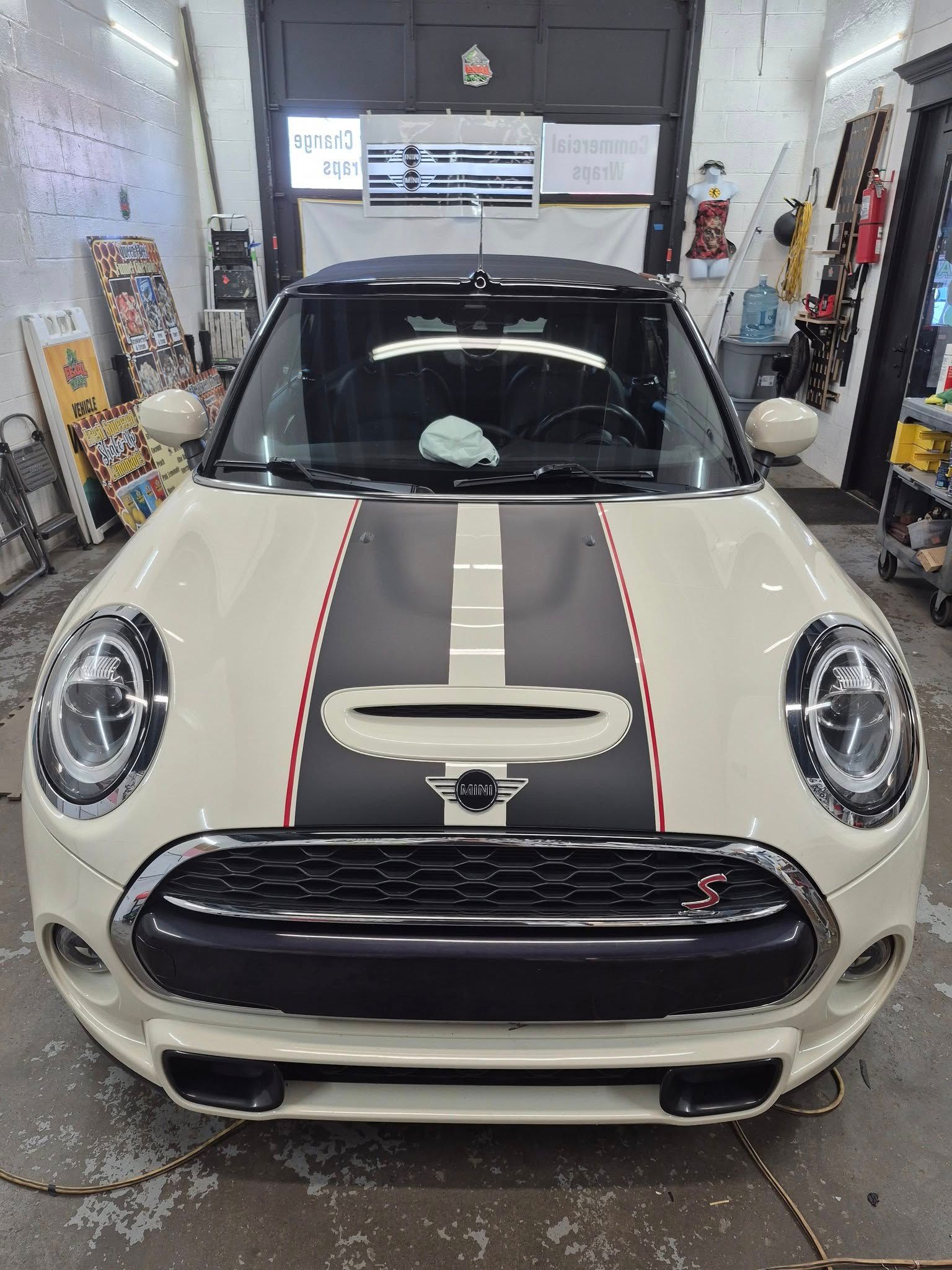 A white mini cooper is parked in a garage.