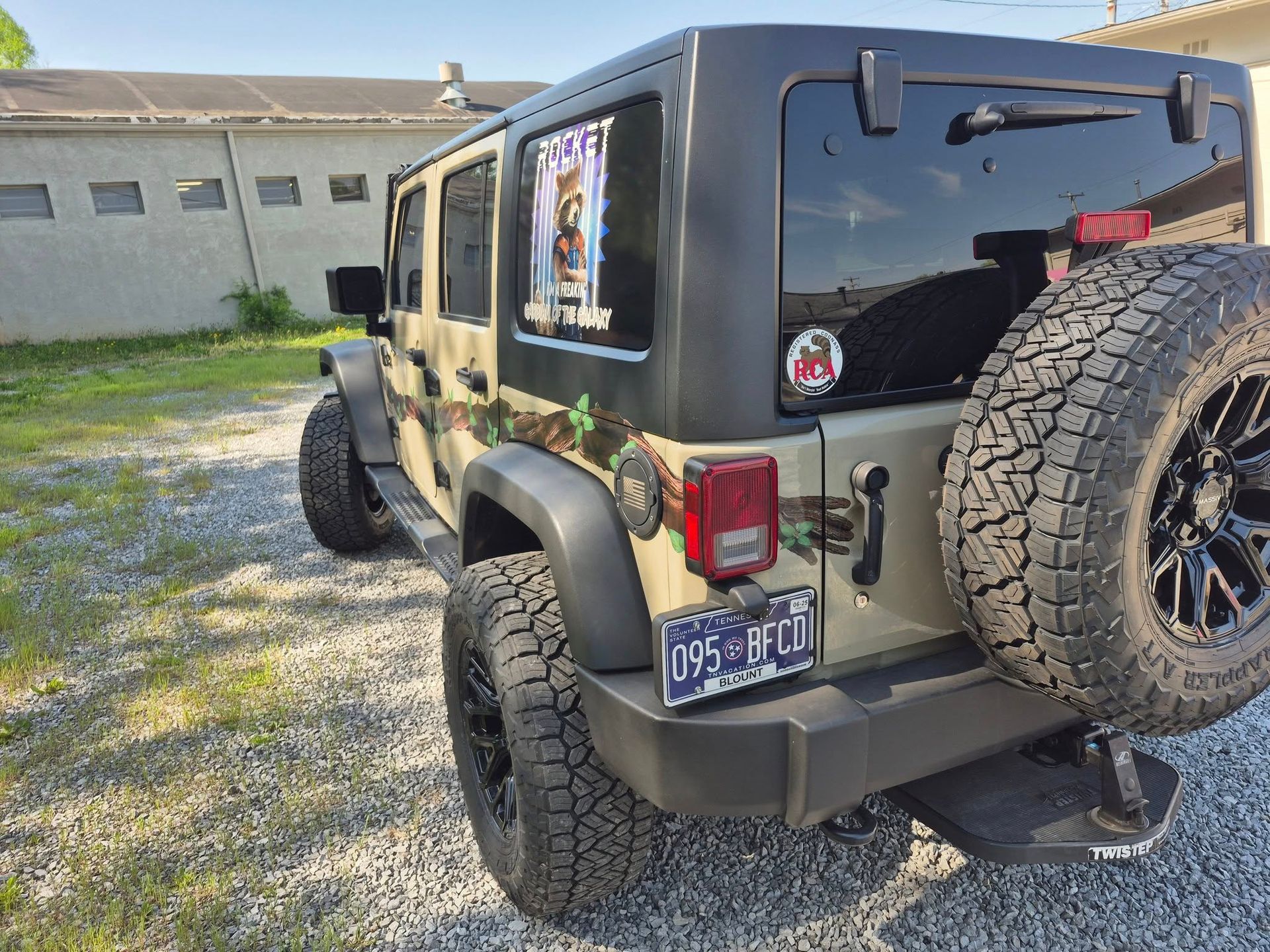 A jeep is parked in a gravel lot in front of a building.