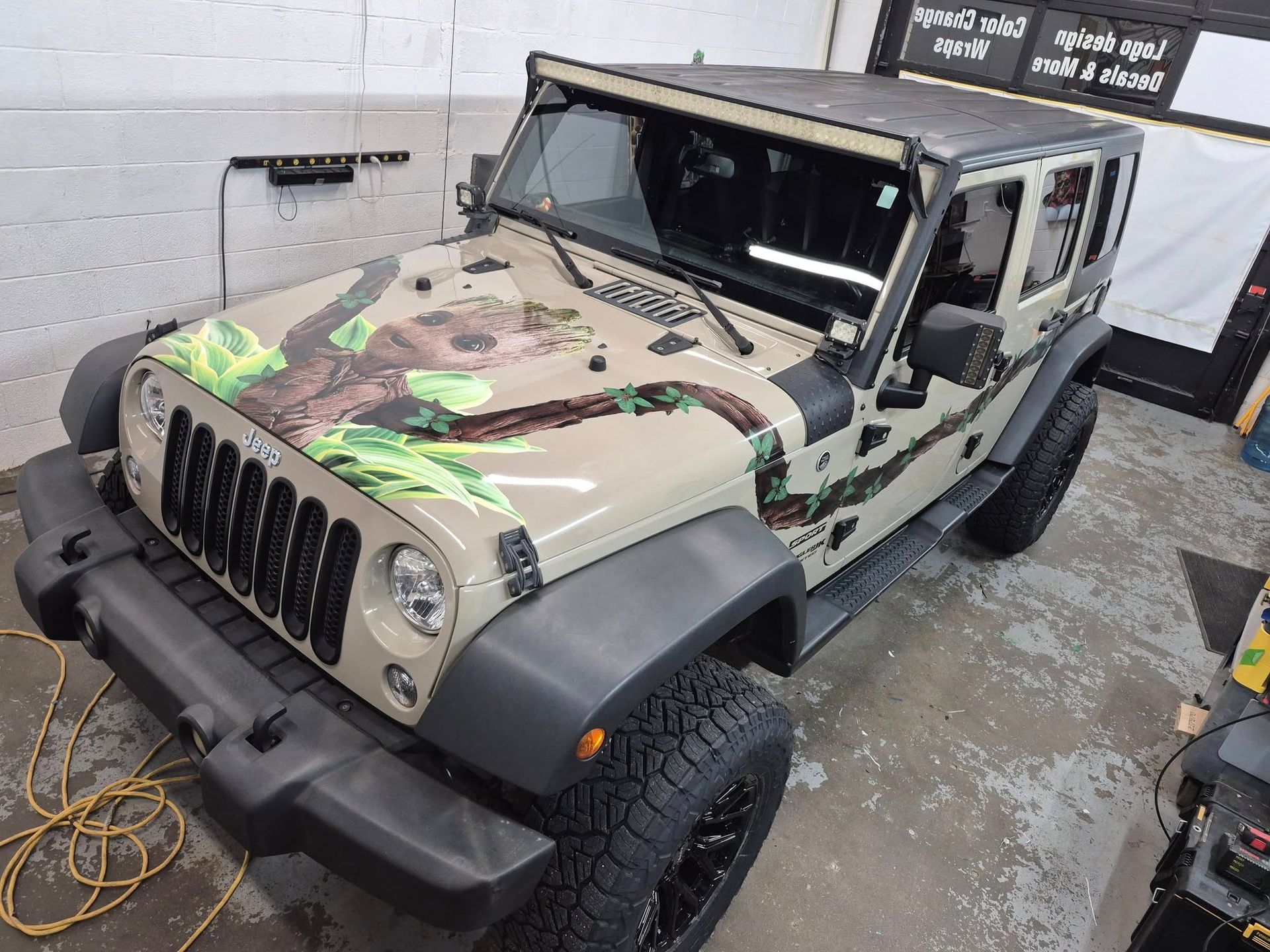 A jeep with a monkey on the hood is parked in a garage.