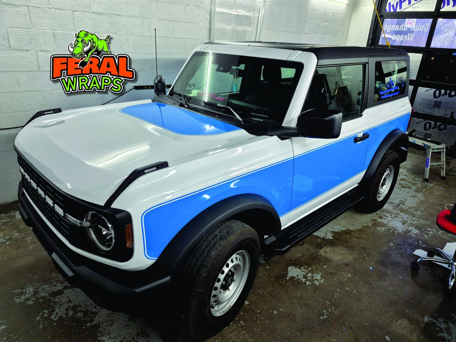 Ford Bronco with white and blue paint scheme, parked inside a garage.