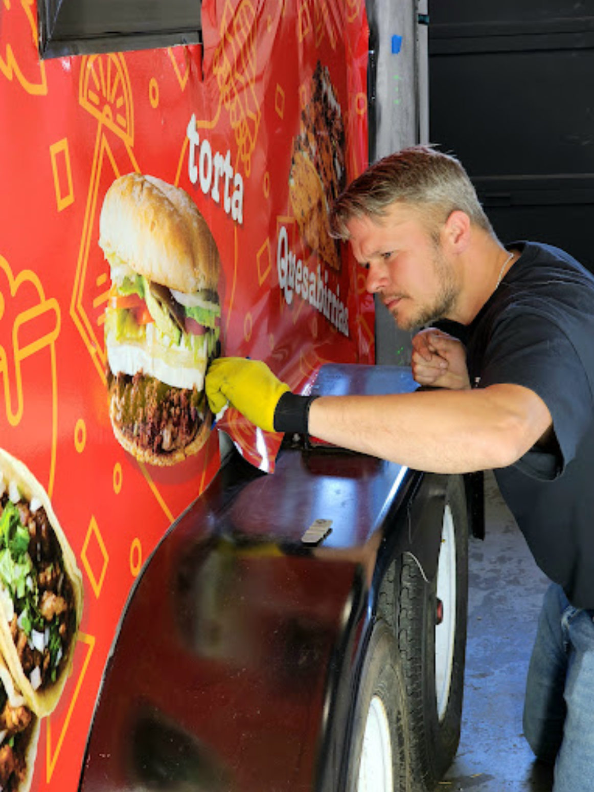 A man is working on a food truck that says torta