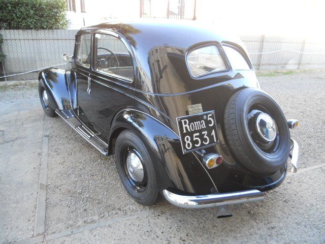 Berlina d'epoca nera parcheggiata all'aperto, vista posteriore con ruota di scorta e targa Roma 5.