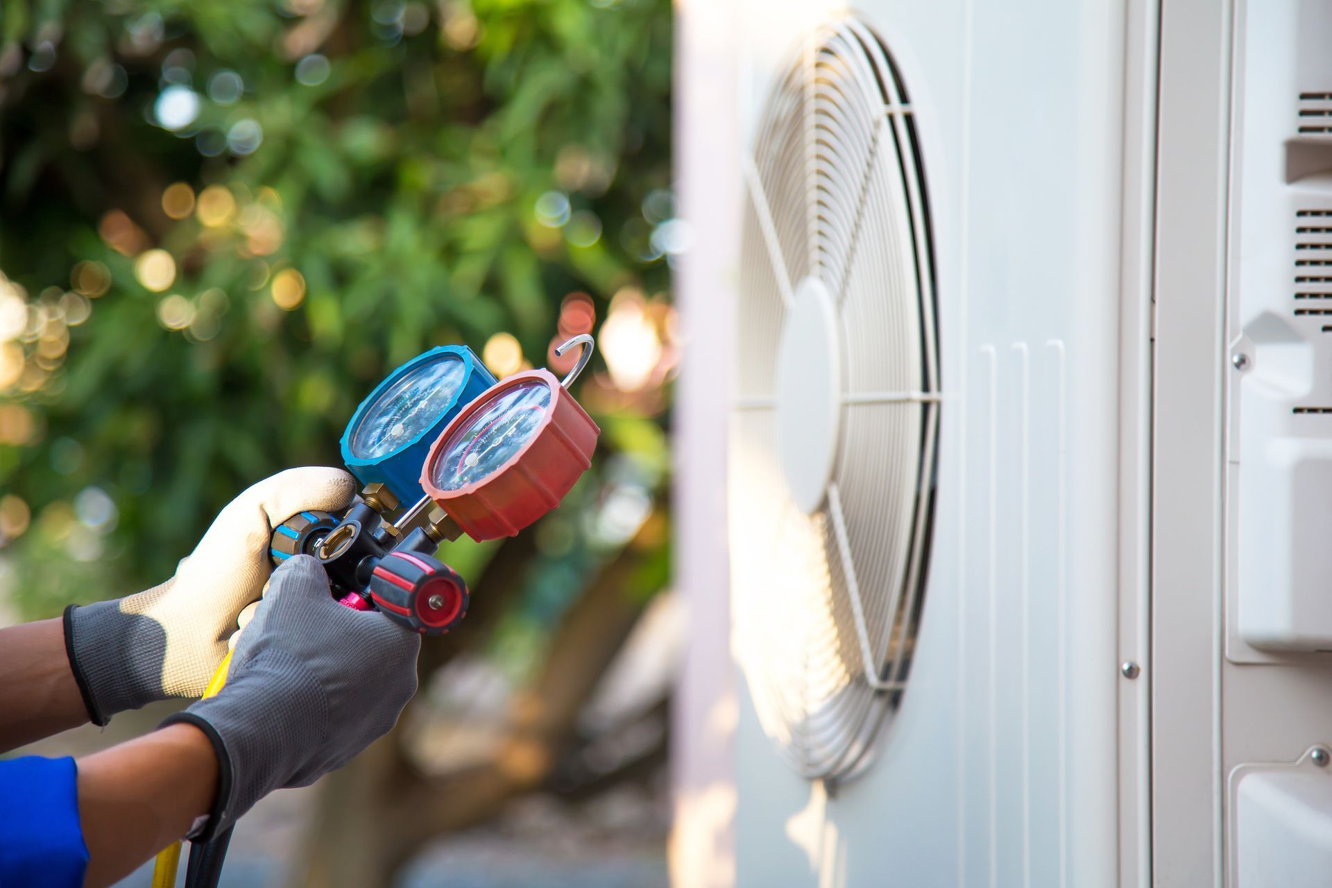 A technician uses gauges to service an outdoor commercial air conditioning unit.