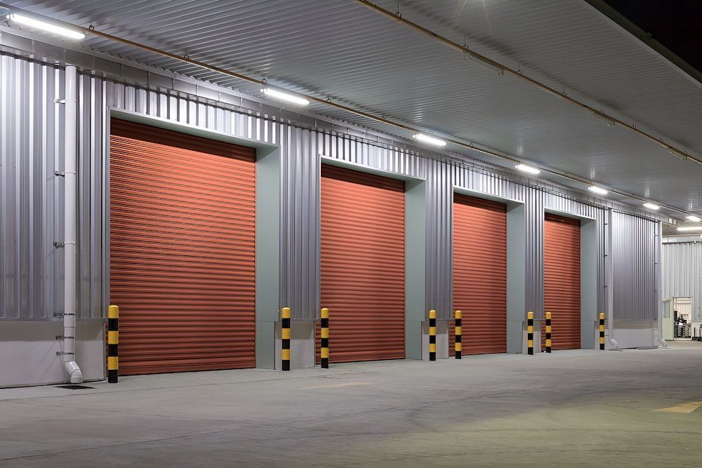 A Row Of Red Garage Doors In A Warehouse At Night — Brunswick Valley Door Centre in Main Arm, NSW