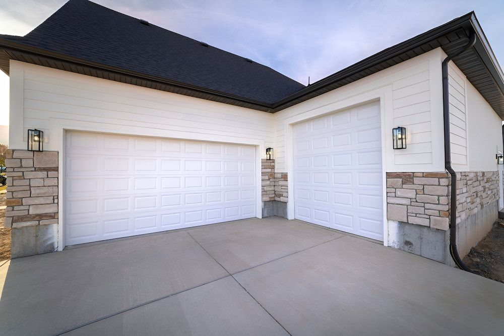 A White House With Two Garage Doors And A Concrete Driveway — Brunswick Valley Door Centre in Mullumbimby, NSW