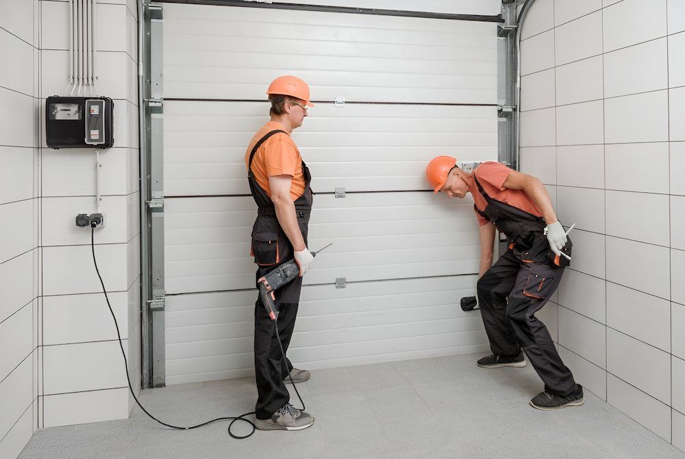 Two Men Are Working On A Garage Door In A Garage — Brunswick Valley Door Centre in Main Arm, NSW