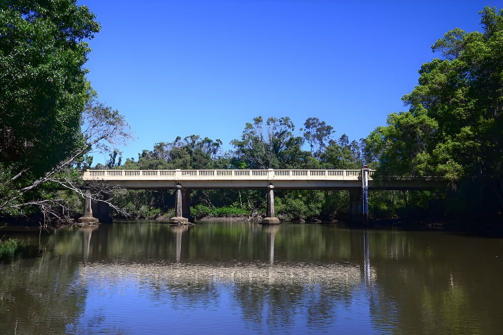 A Bridge Over A River Surrounded By Trees On A Sunny Day — Brunswick Valley Door Centre in Mullumbimby, NSW