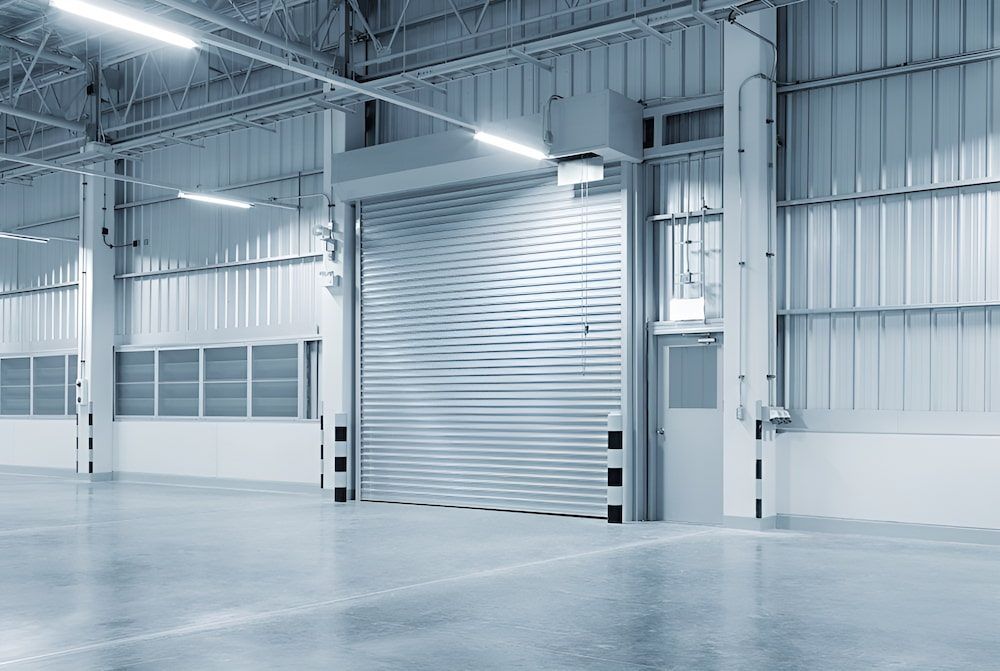An Empty Warehouse With A Rolling Door And A Concrete Floor — Brunswick Valley Door Centre in Main Arm, NSW