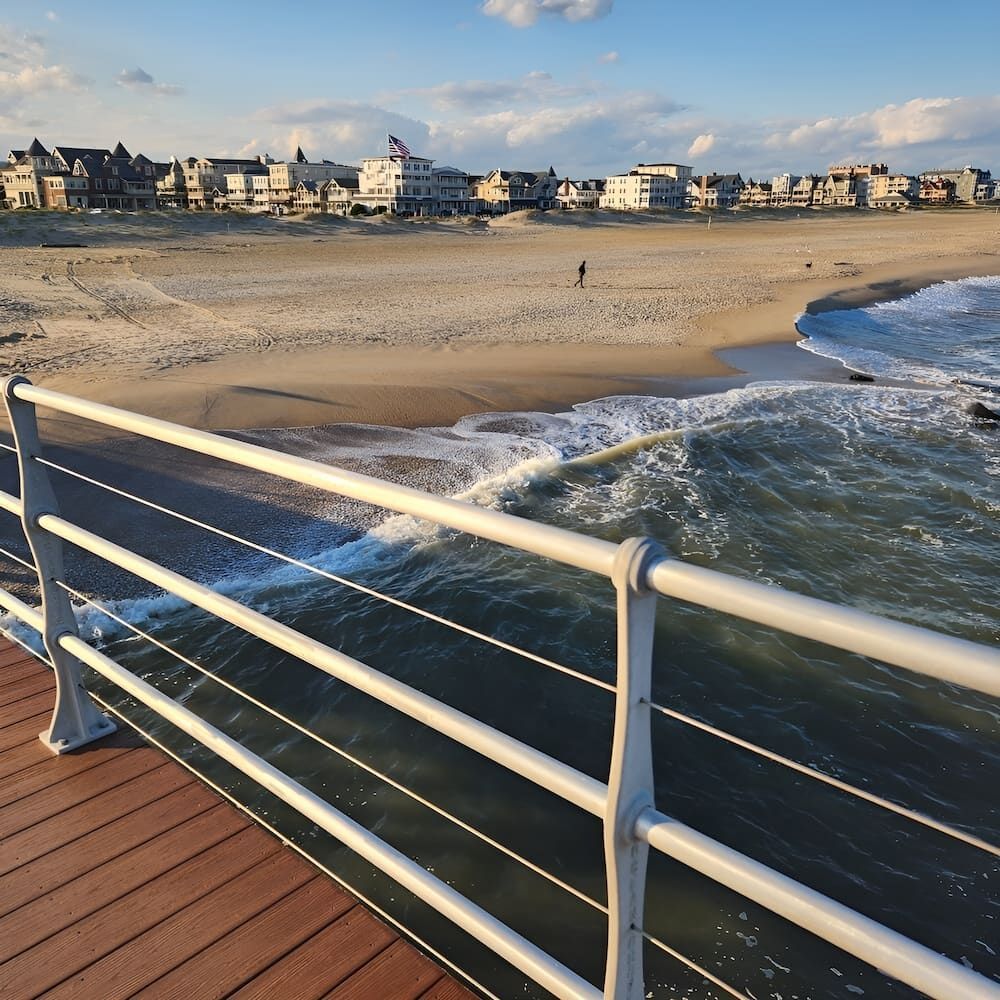A View Of A Beach From A Pier With A White Railing — Brunswick Valley Door Centre in Ocean Shores, NSW