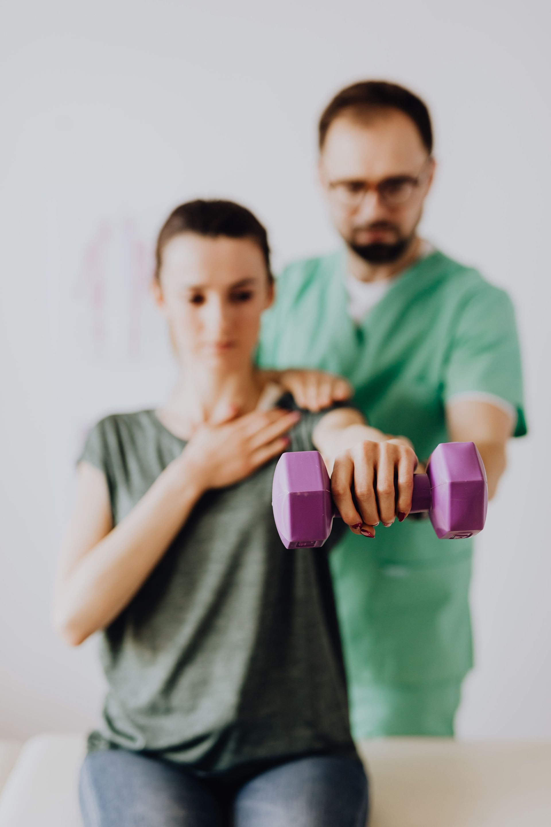 A person applies a black kinesiology tape strip to a knee in a clinical setting.