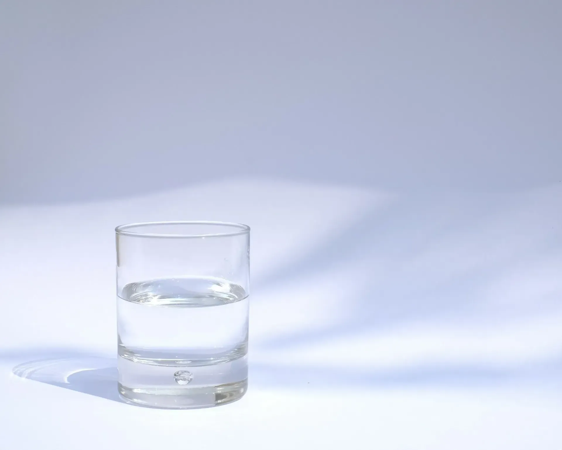 A glass of water is sitting on a white table.