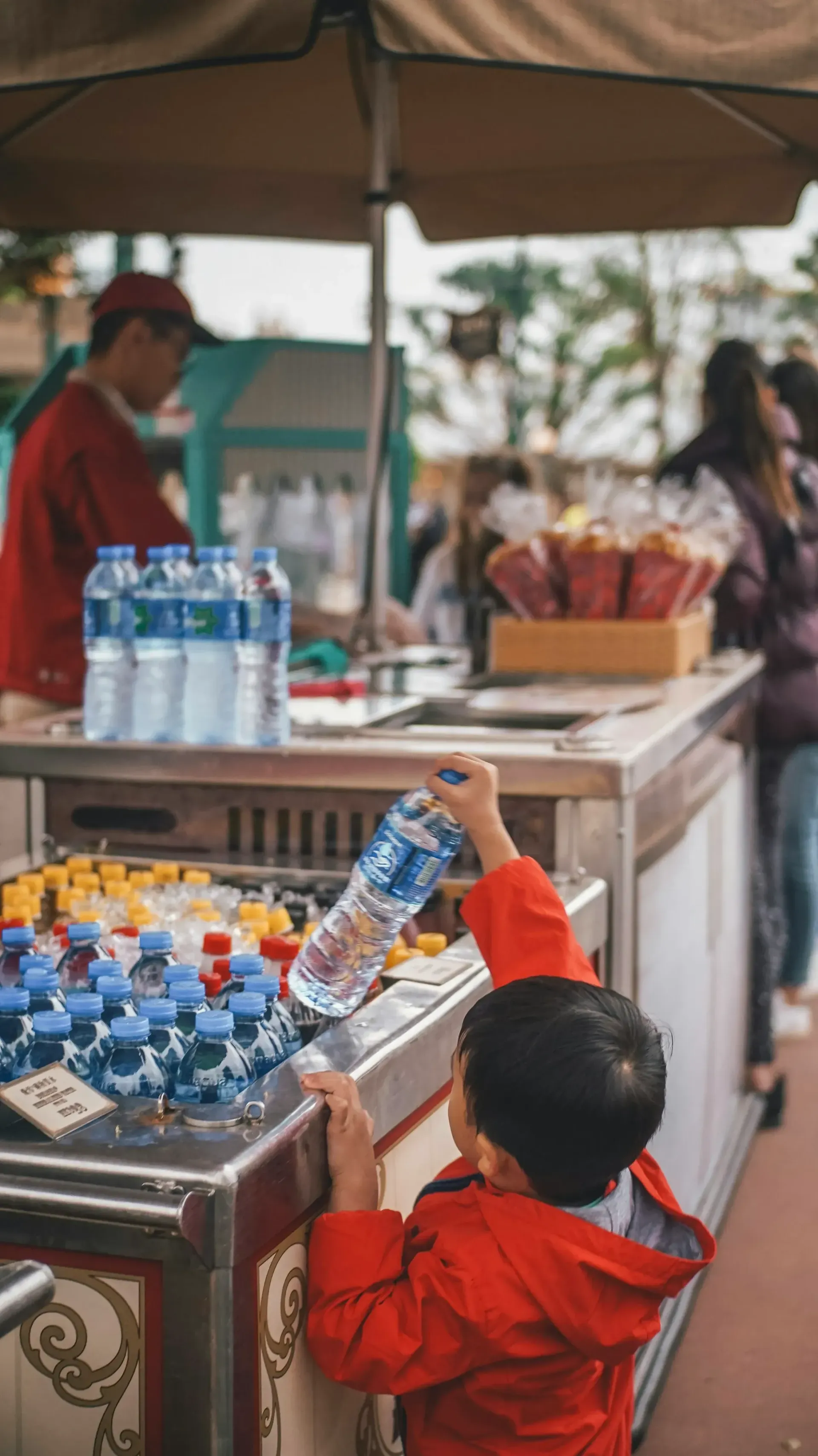 A young boy is reaching for a bottle of water.