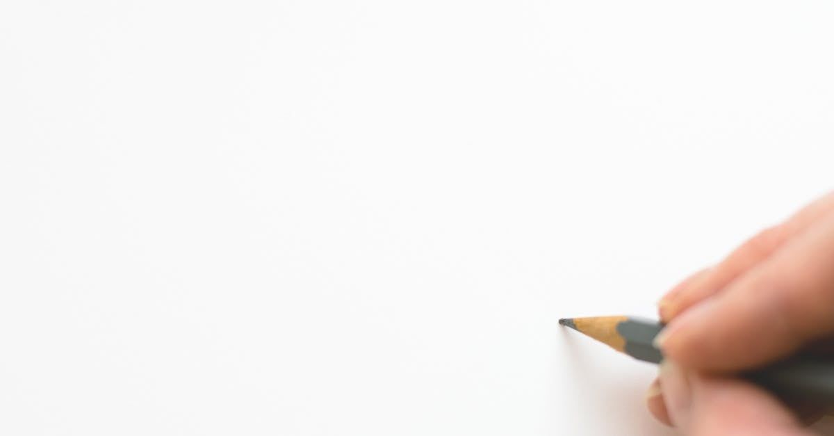 Hand holding a pencil over a blank white page