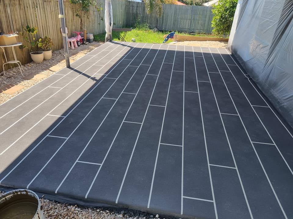 Black Patio Flooring With White Lines Resembling Wood Planks — SRS Concreting In Glenvale, QLD