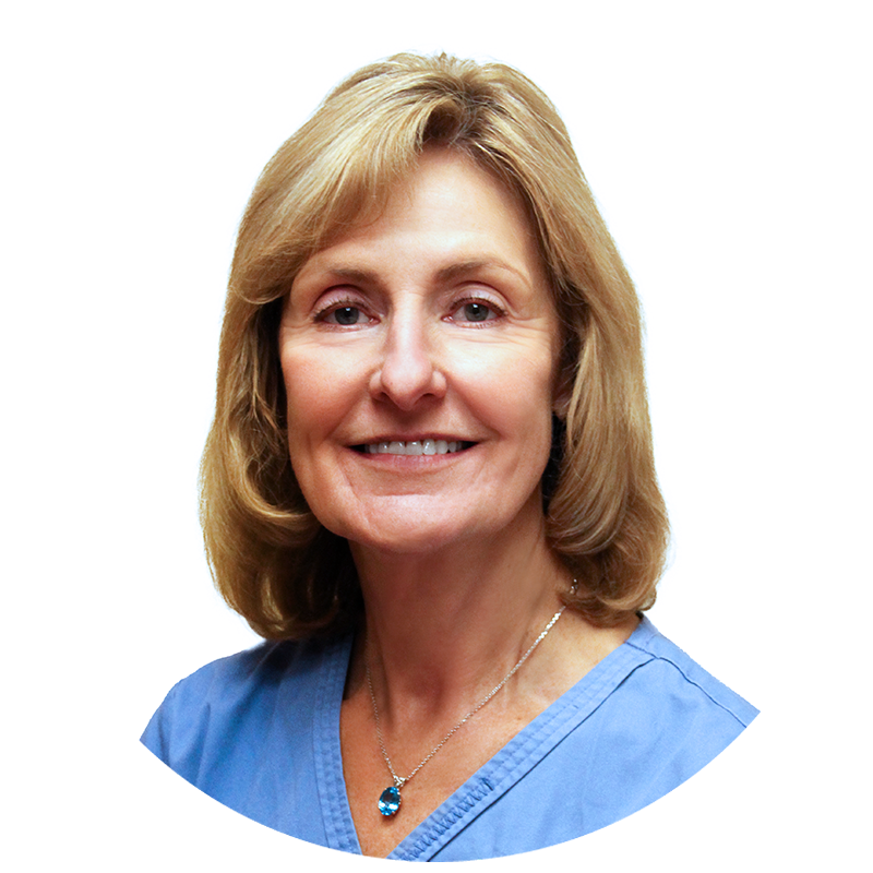A woman wearing a blue scrub top and a necklace smiles for the camera