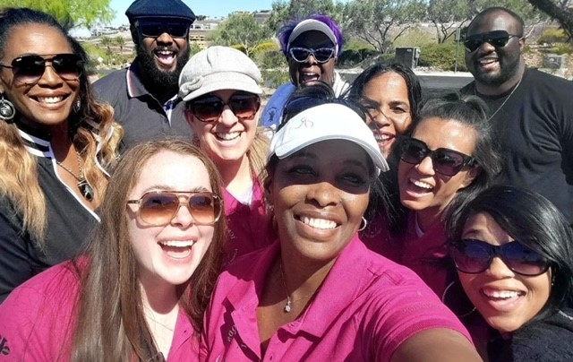 A group of people are posing for a picture and one woman is wearing a pink shirt