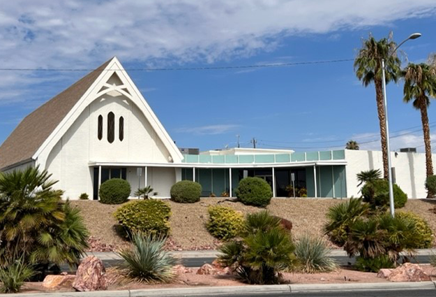 A white church with palm trees in front of it