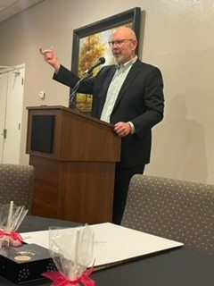 A man in a suit is giving a speech at a podium