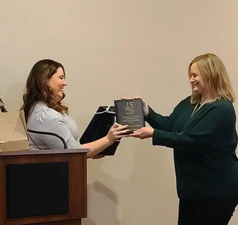 Two women are holding a plaque that says 15 on it