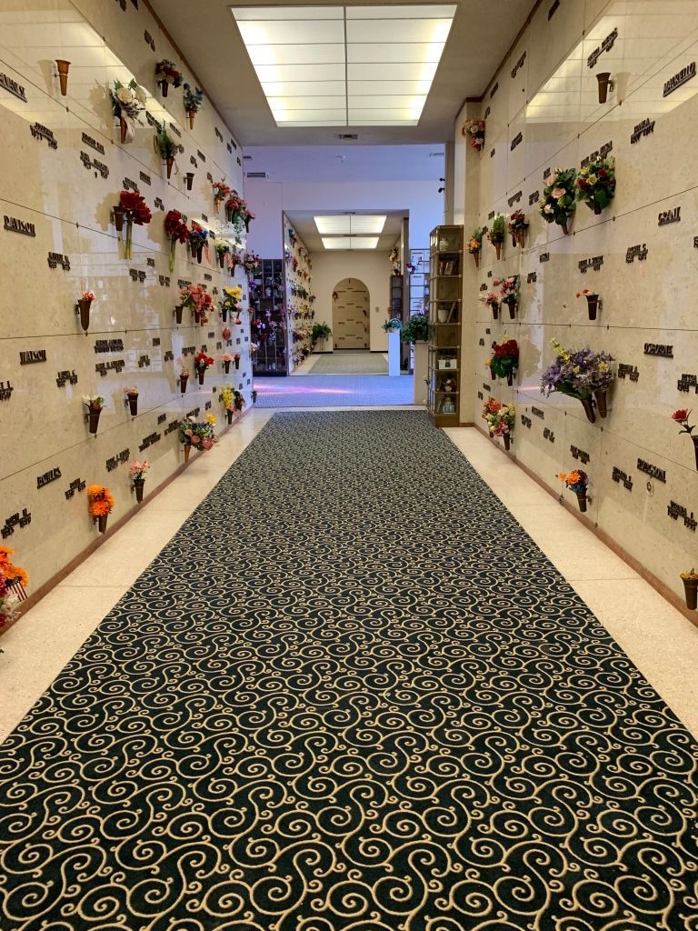 A long hallway in a cemetery with flowers on the walls.