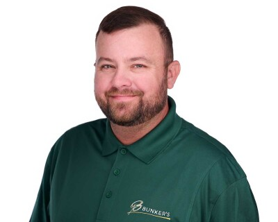 A man with a beard is wearing a green polo shirt.