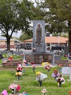A cemetery with lots of flowers and a statue of a woman