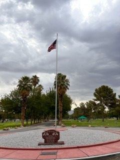 An american flag is flying on a pole in a park