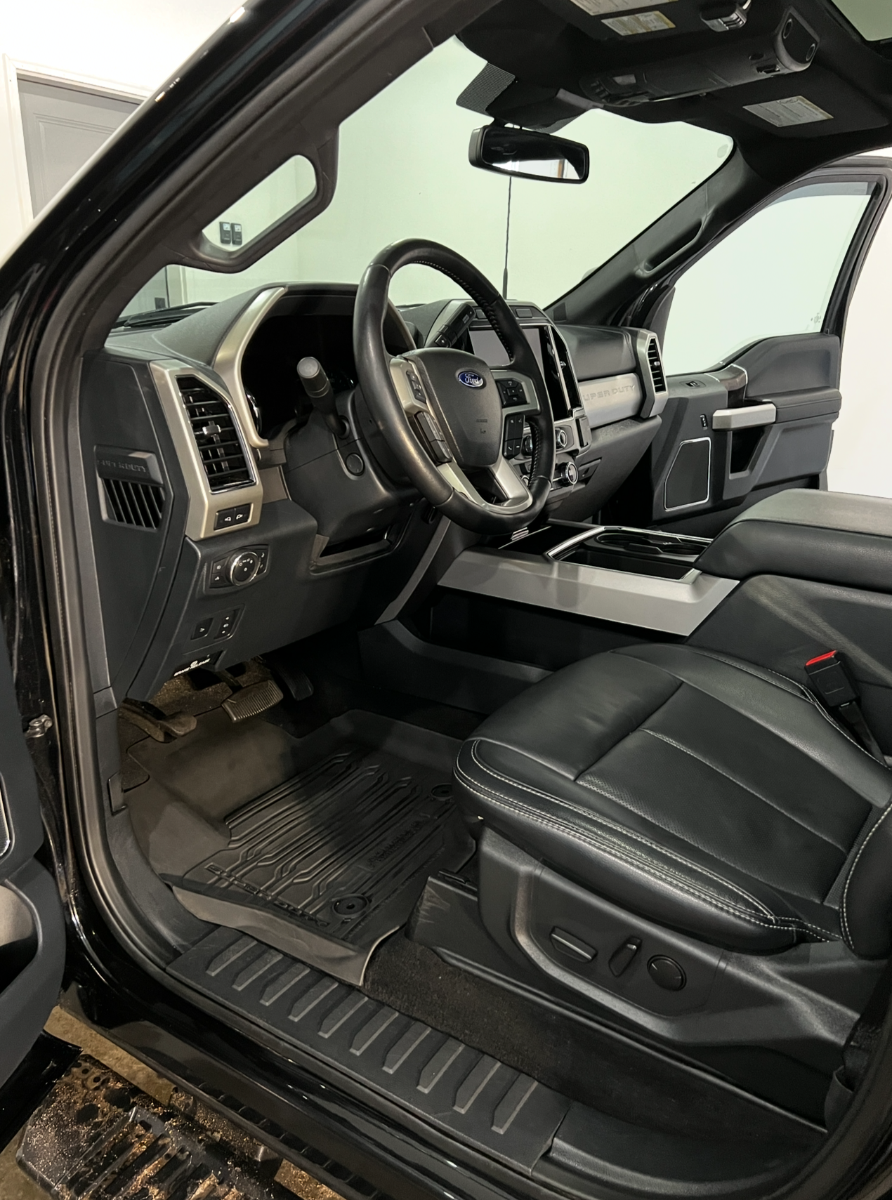 The interior of a black ford f150 truck with the door open.