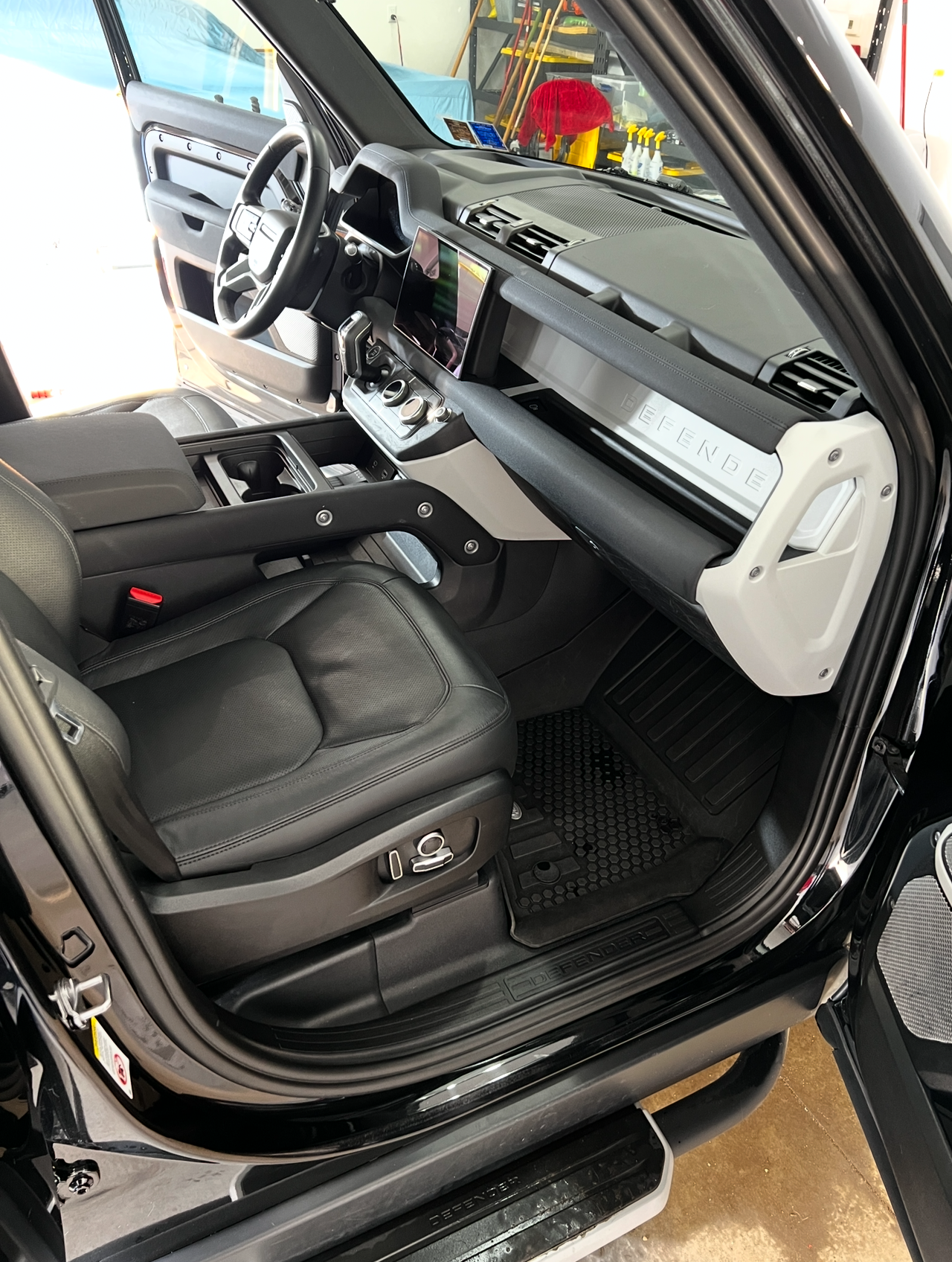The interior of a black land rover defender with the door open.