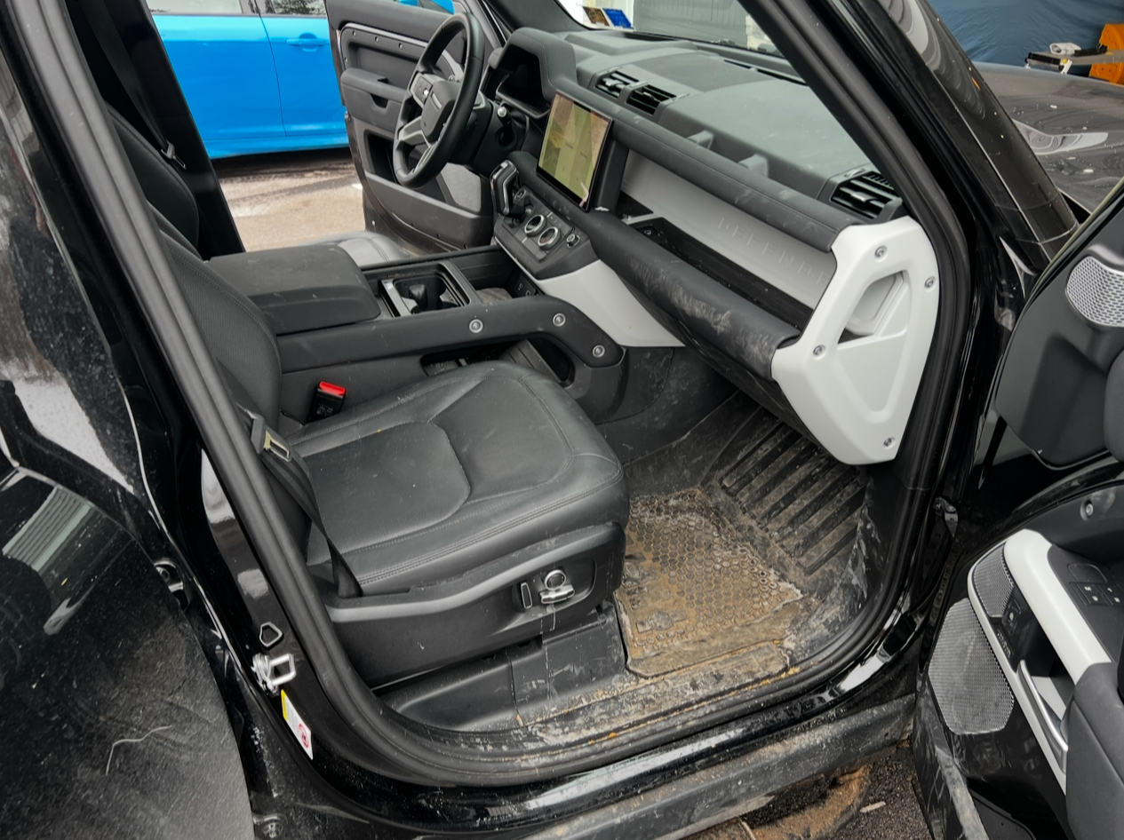 The inside of a black land rover defender with the door open.