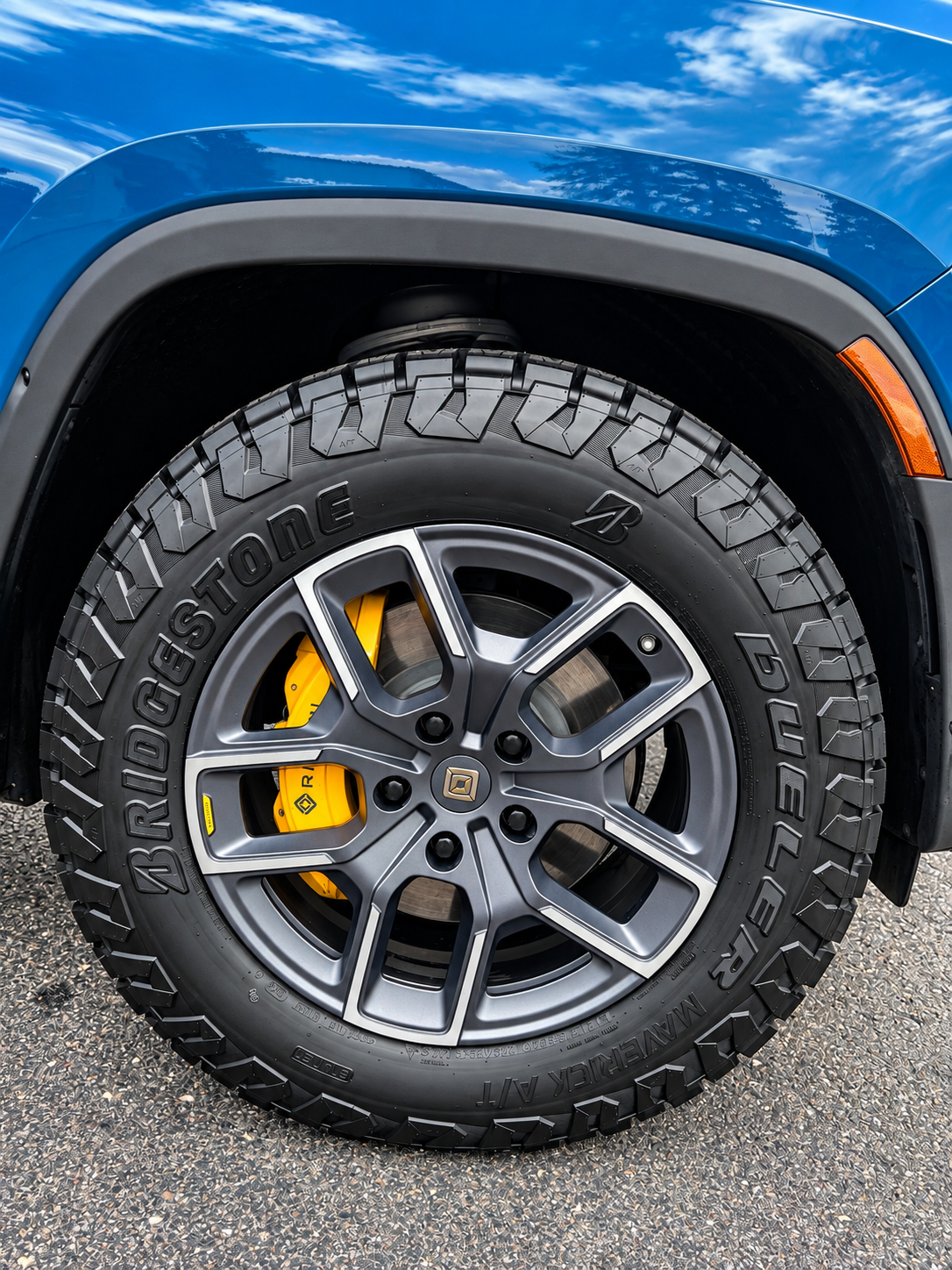 Close-up of a blue SUV wheel with rugged tire and yellow brake caliper