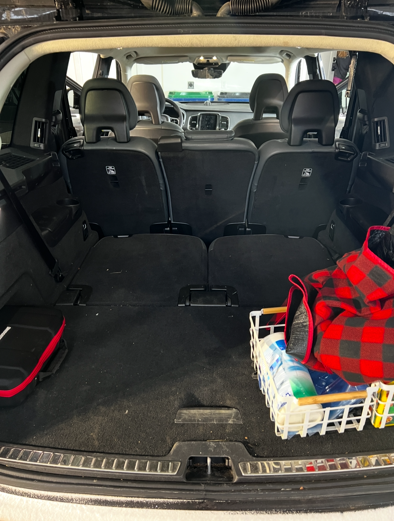 The trunk of a car with a basket of groceries in it.