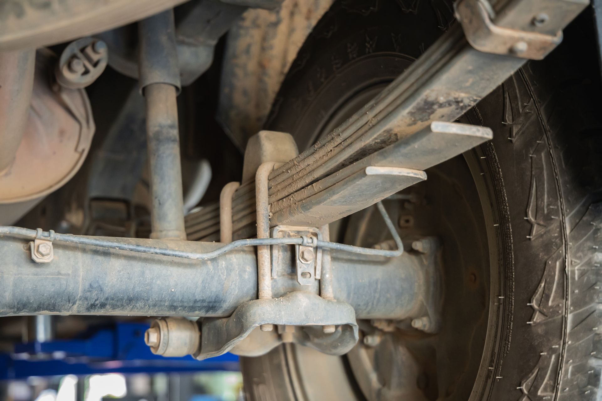 Close-up of a vehicle’s rear suspension and leaf spring near the wheel