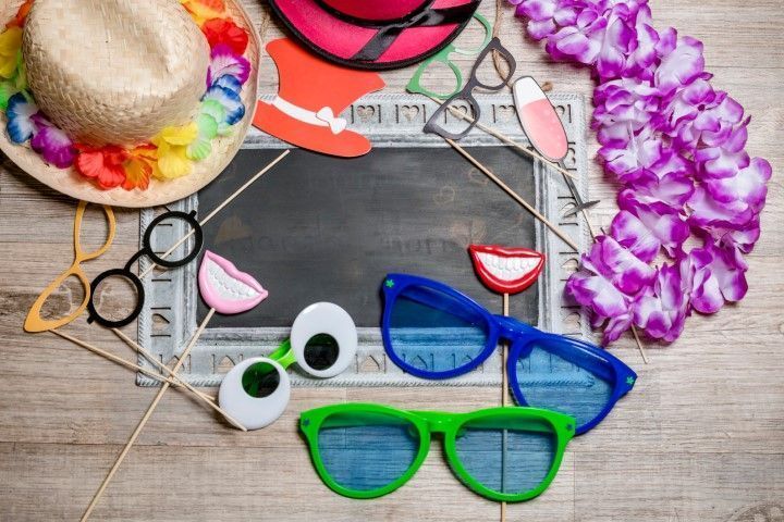 Colorful summer accessories on a wooden table: sunglasses, a straw hat, a floral lei, and seashell decor