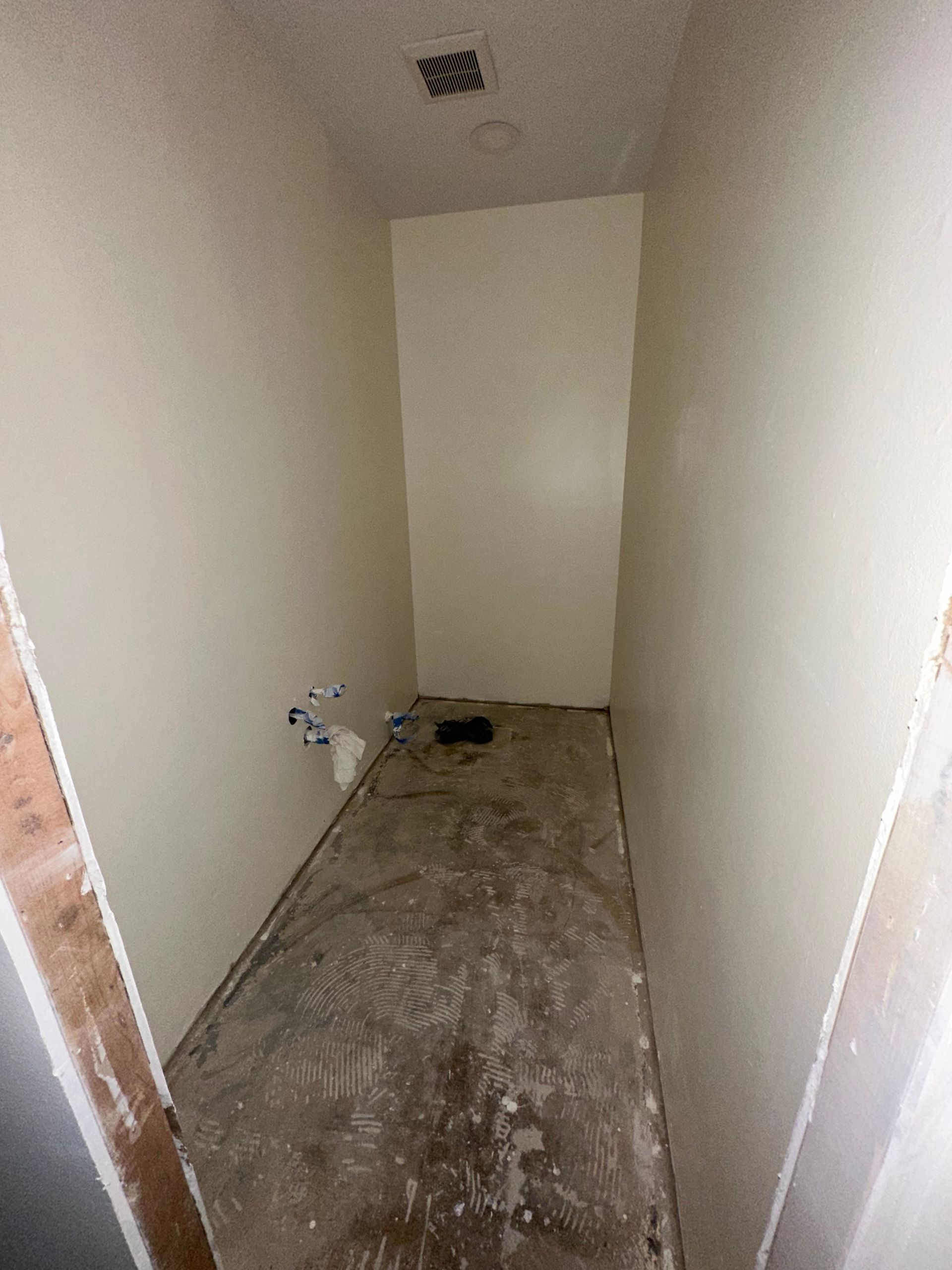A very long narrow room with a toilet in it.