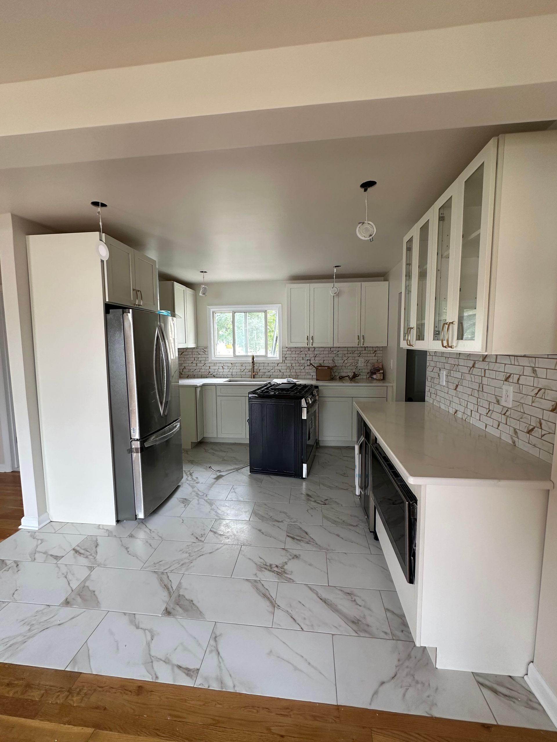 A kitchen with white cabinets and marble floors