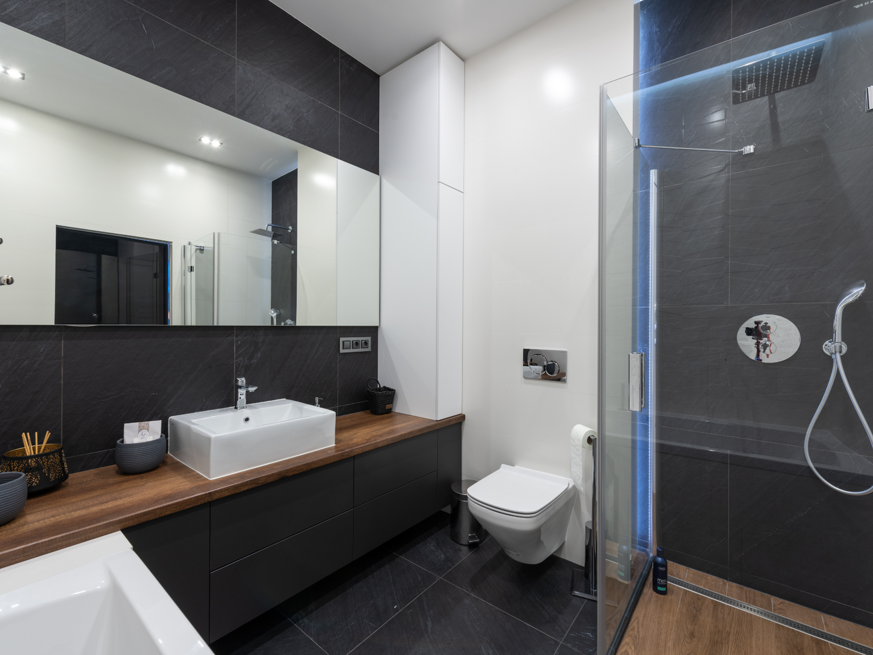 A bathroom with a sink , toilet , shower and mirror.