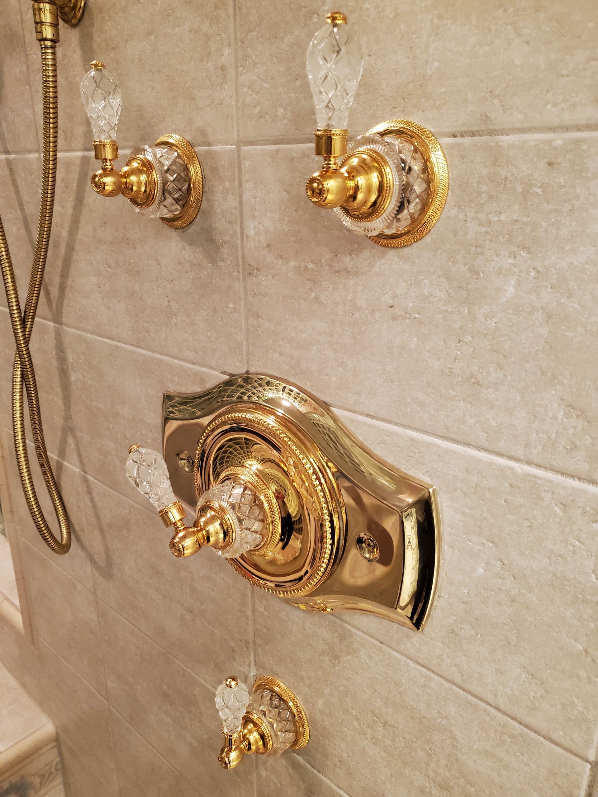 New gold-finish shower trim with clear decorative handles and a wide plate around the main control.