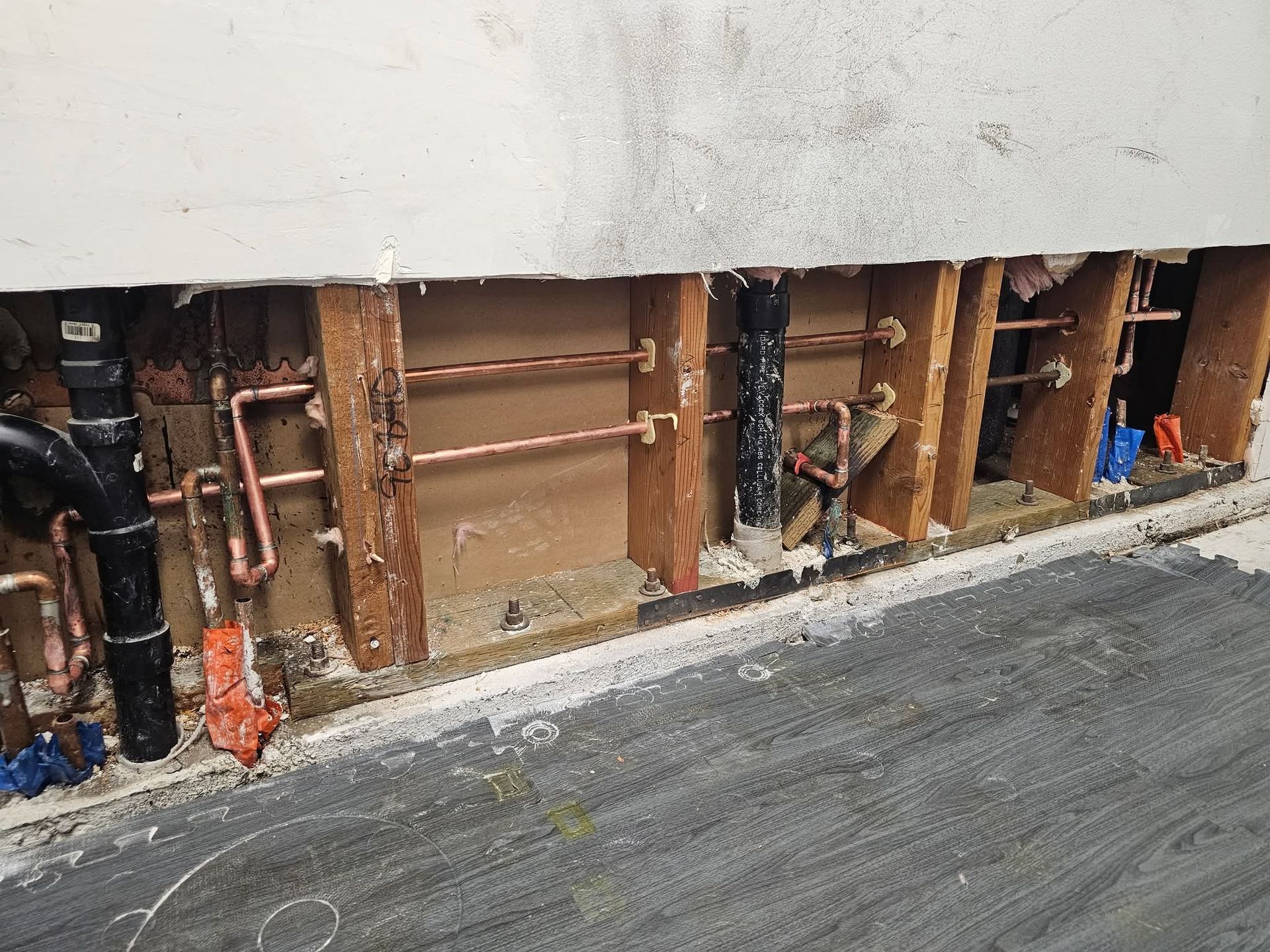 Exposed copper water lines and plumbing inside an open bathroom wall