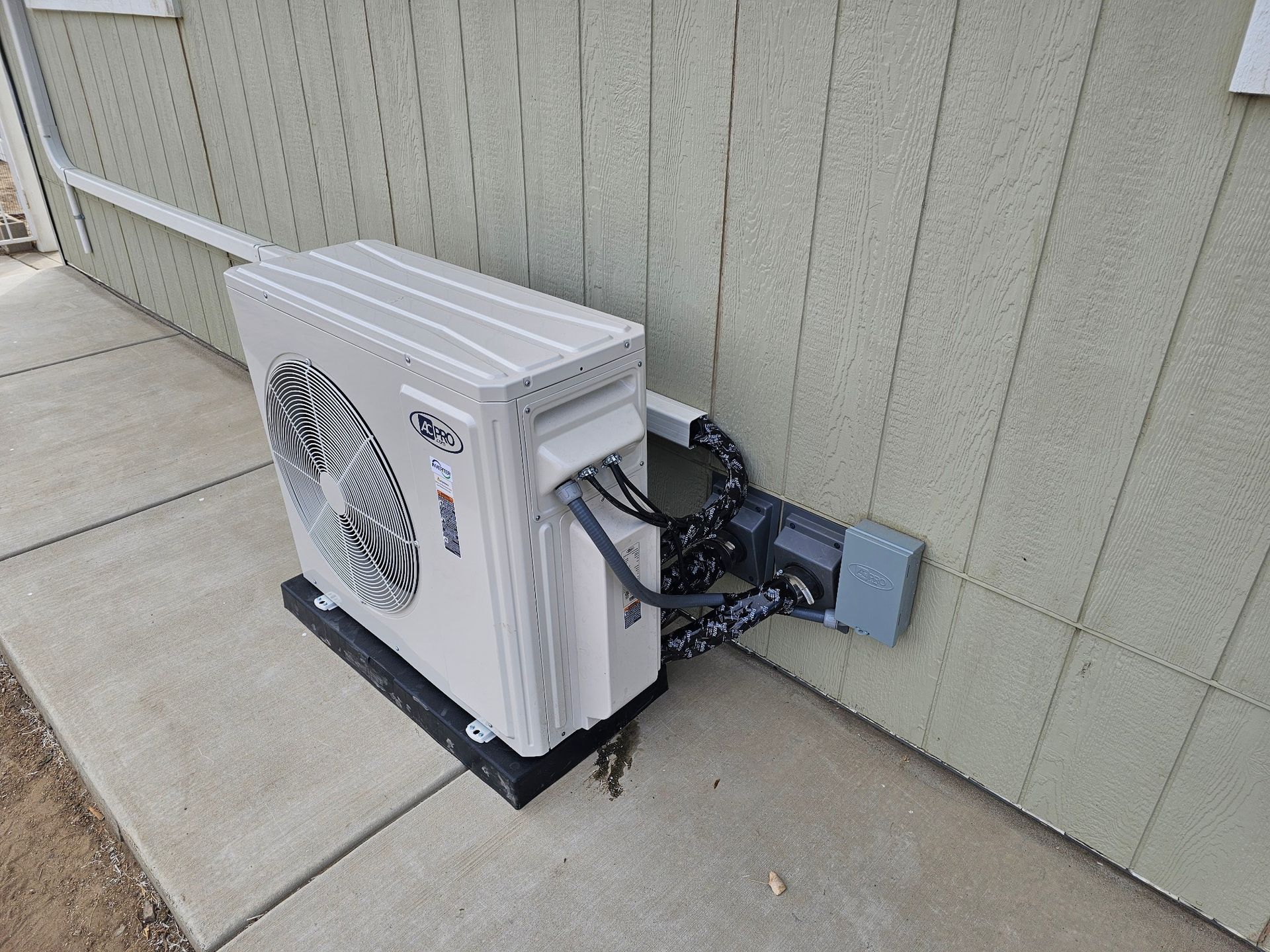 A white air conditioner is attached to the side of a building.