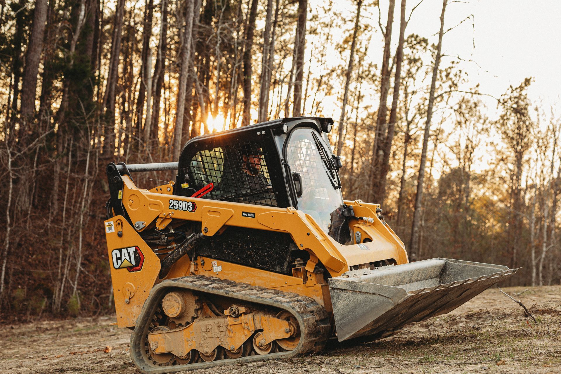 A man is driving a bulldozer through a forest.