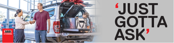 Car dealership scene with two people beside a car and a red “Just Gotta Ask” sign — Ol Mate 4x4 in Tuggerah, NSW