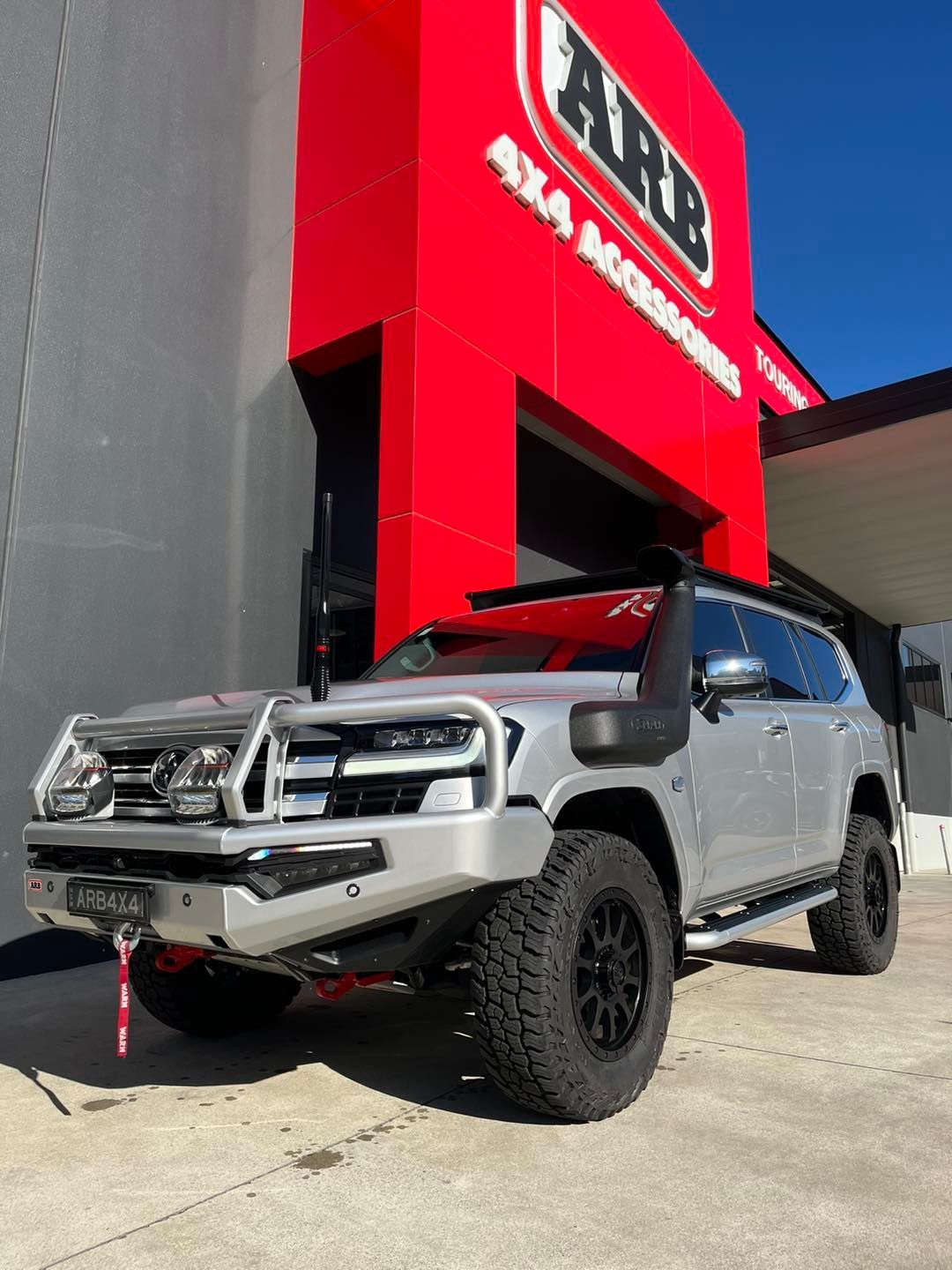 Silver off-road SUV parked by a red Auto One storefront, angled in bright sunlight — Ol Mate 4x4 in Tuggerah, NSW