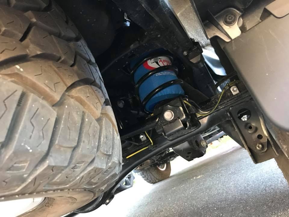 Undercarriage of a vehicle showing a large off-road tire and blue suspension spring — Ol Mate 4x4 in Tuggerah, NSW