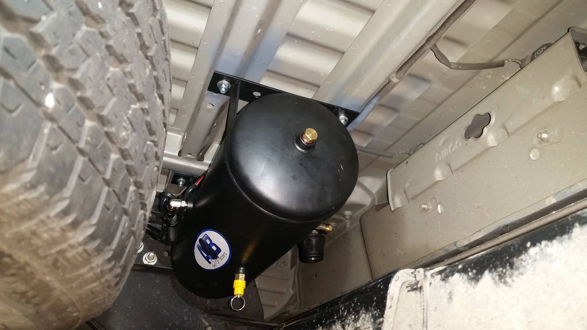 Black cylindrical device with a white label, wedged in a narrow space between a tire and metal structure — Ol Mate 4x4 in Tuggerah, NSW