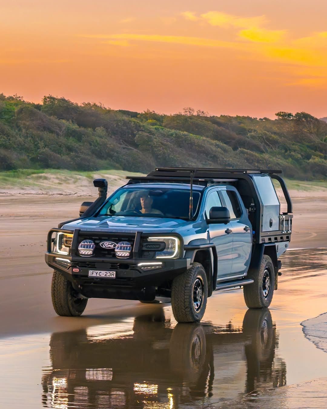 Black pickup truck driving on wet beach sand at sunset with orange sky and reflections — Ol Mate 4x4 in Tuggerah, NSW
