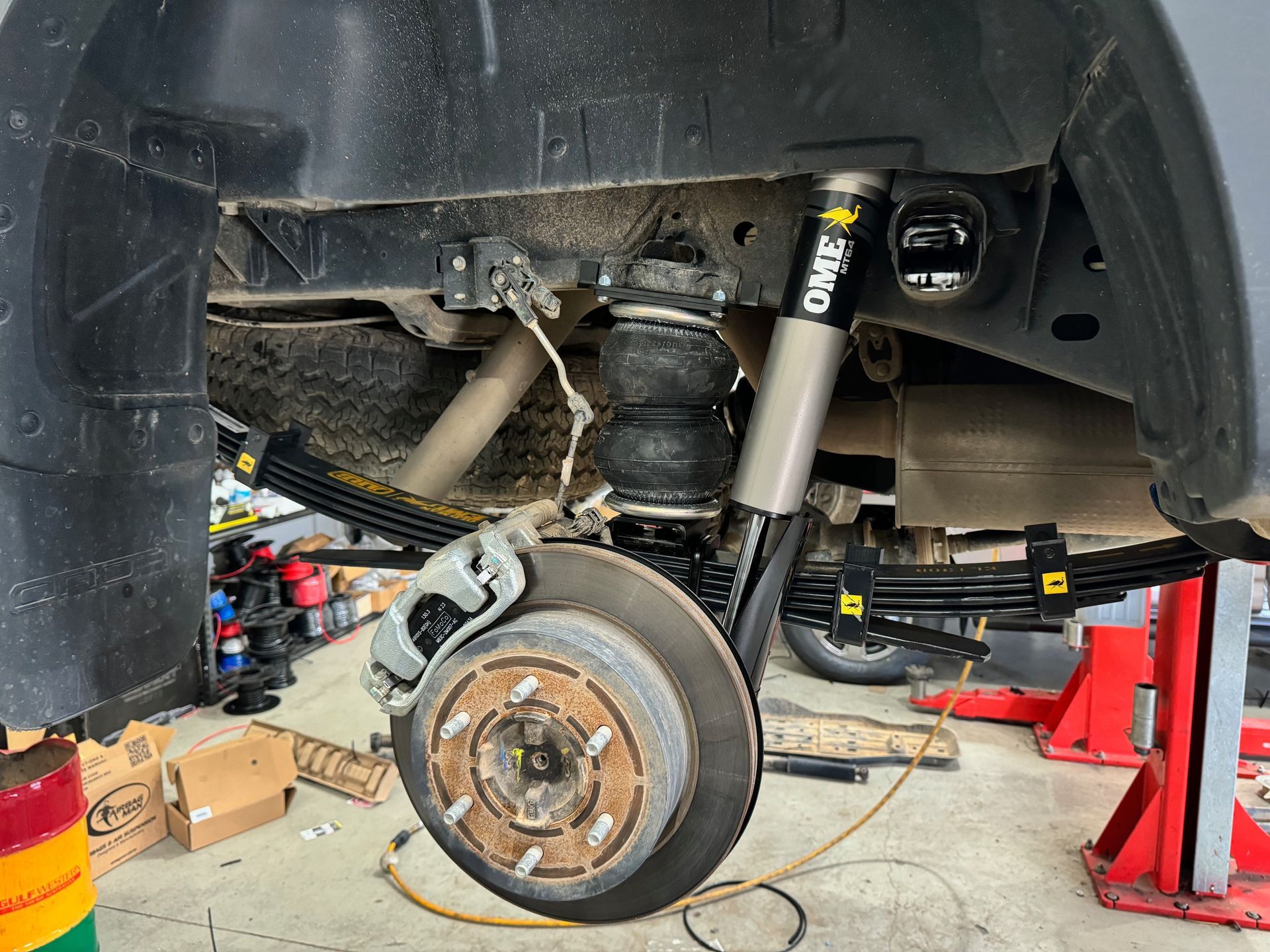 Car wheel and suspension removed in a garage, showing brake rotor, strut, and undercarriage — Ol Mate 4x4 in Tuggerah, NSW