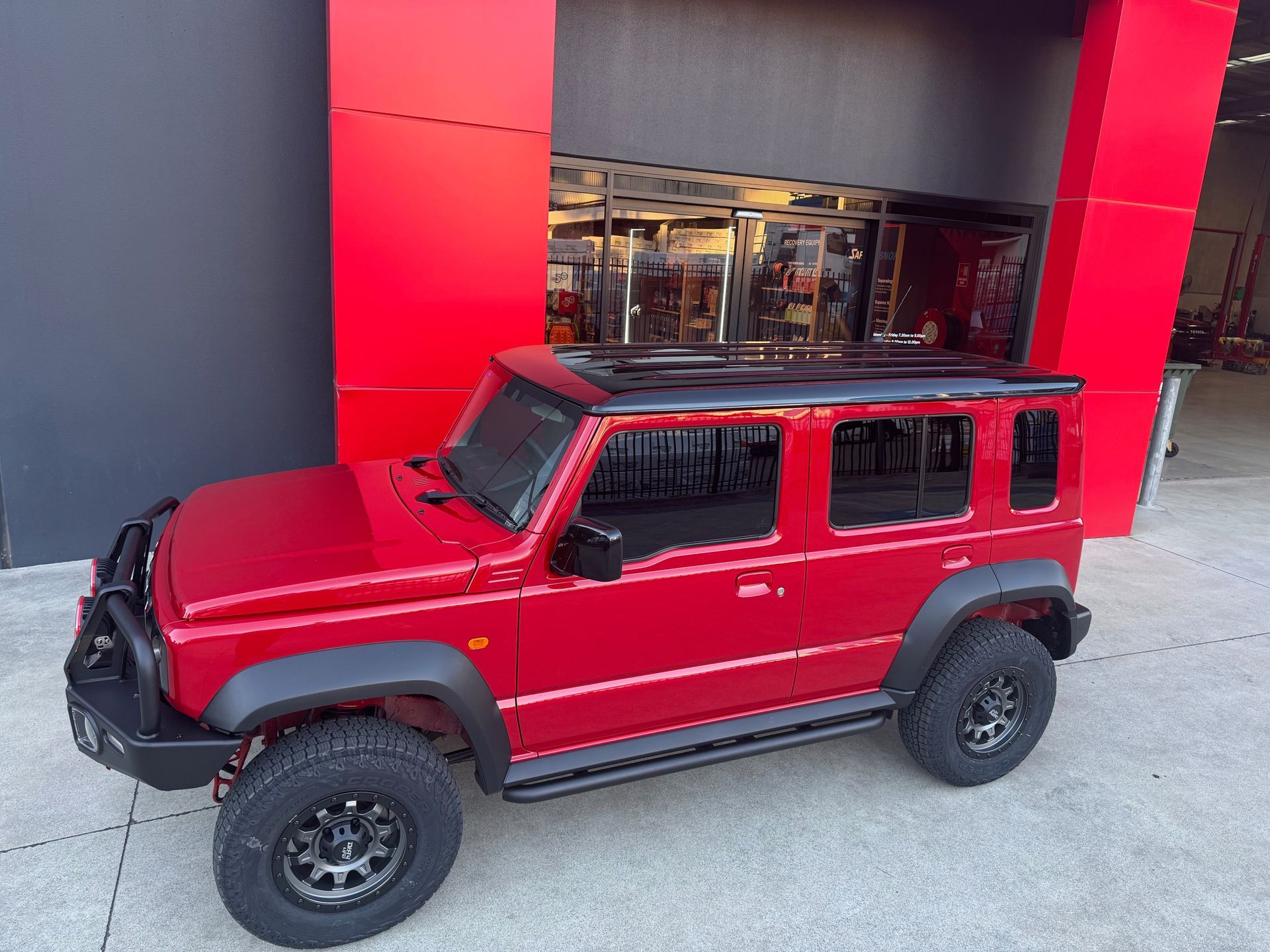 Red four-door SUV parked outside a building with bright red pillars and a glass entrance — Ol Mate 4x4 in Tuggerah, NSW