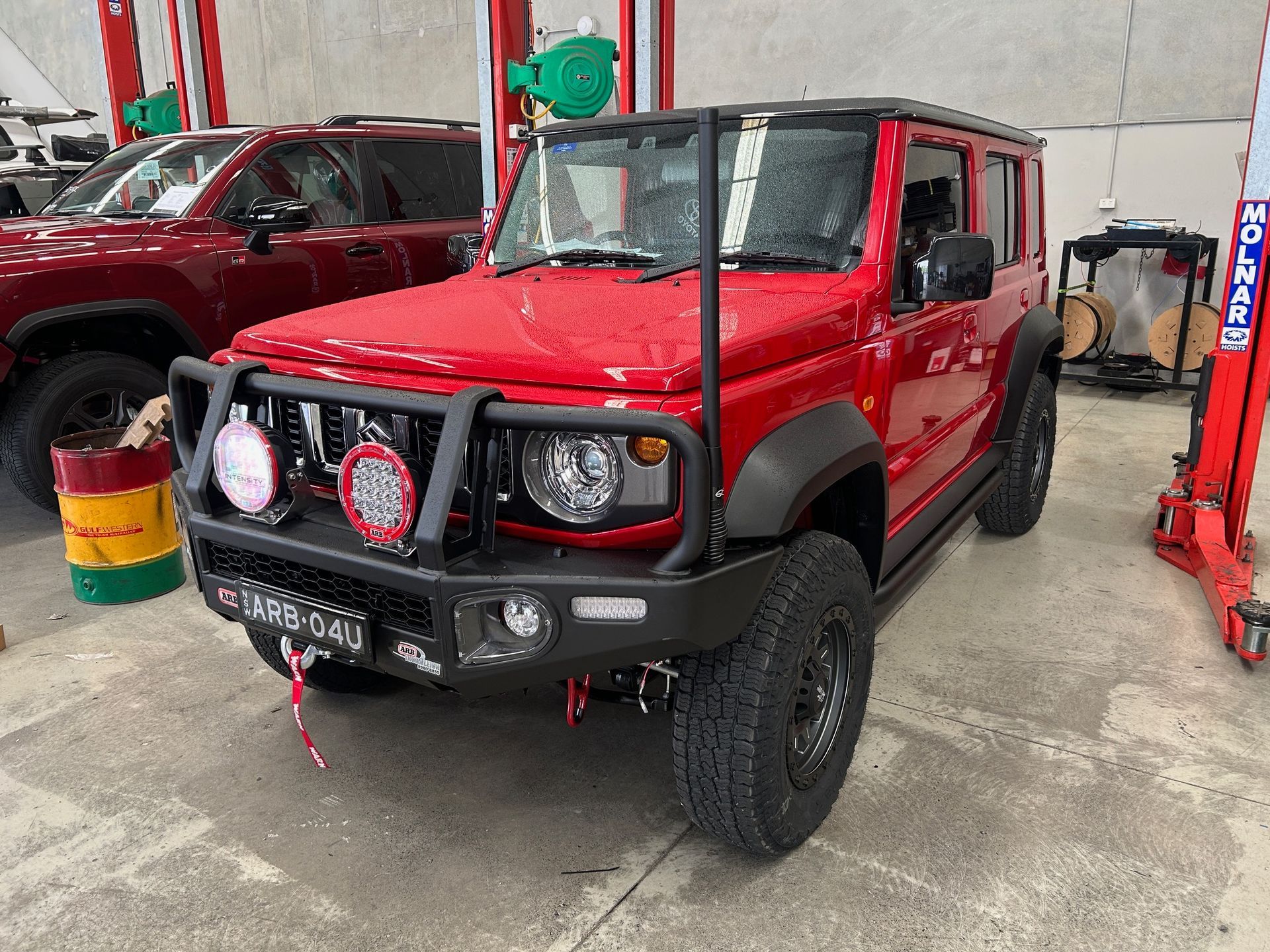 Red off-road SUV with roof rack and front lights in a workshop bay — Ol Mate 4x4 in Tuggerah, NSW