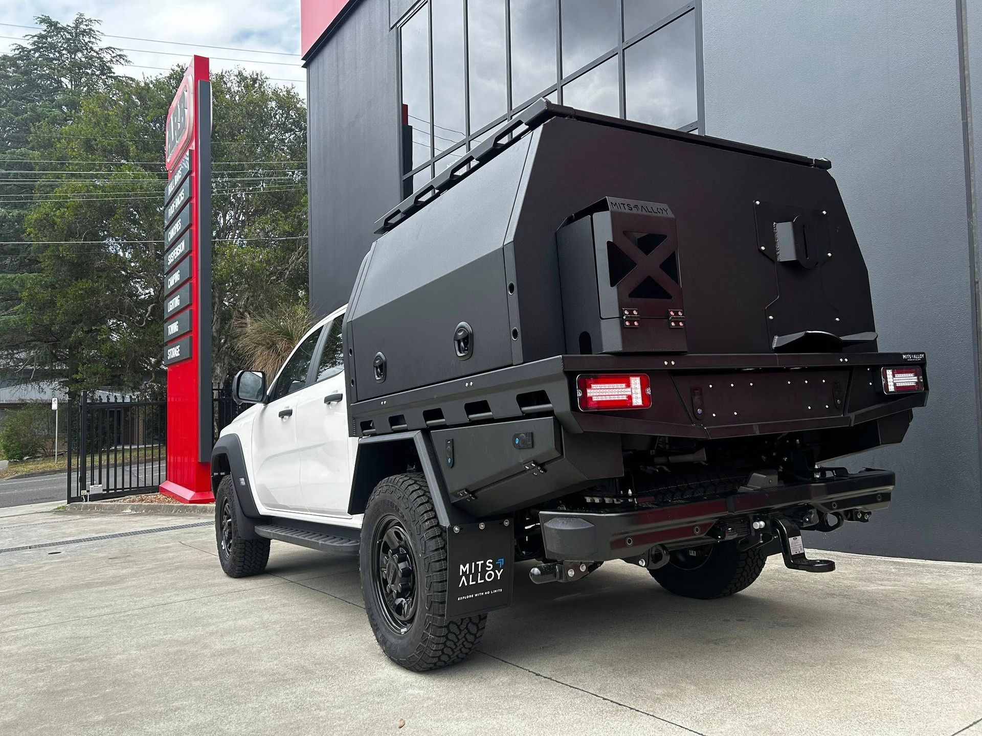 White off-road pickup with black utility box parked outside a modern building — Ol Mate 4x4 in Tuggerah, NSW